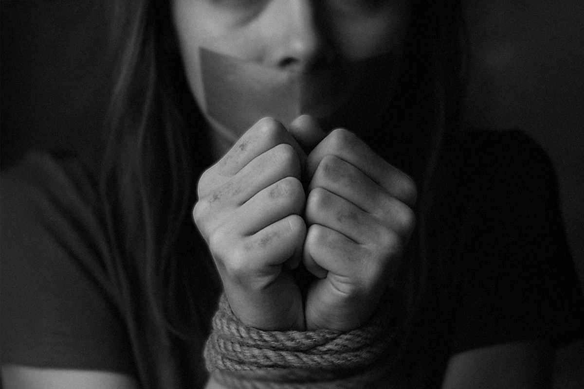A woman with her mouth taped and hands bound.